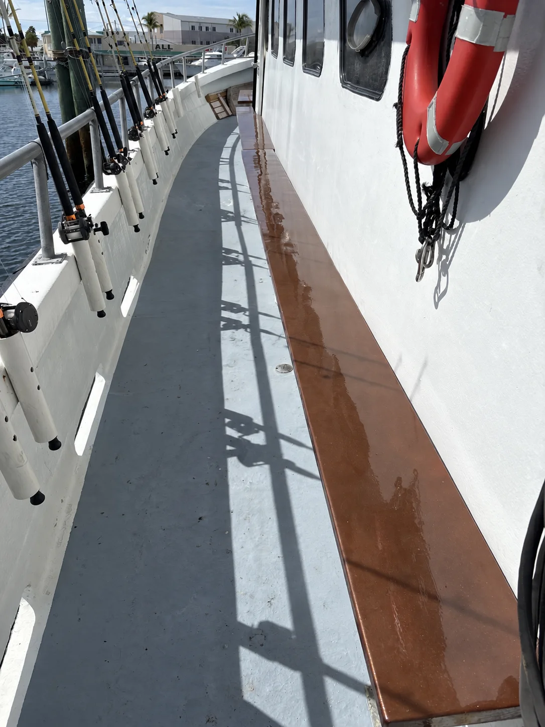 Long wooden bench beside fishing rods and deck-mounted rod holders on the Gulfstream IV side deck